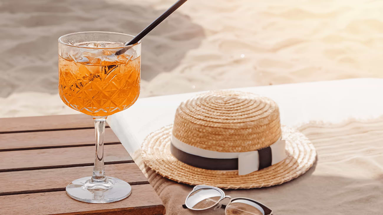 A picture with a vacation atmosphere, a straw hat, a drink and sunglasses