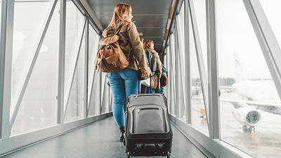 אישה בדרך למטוס בשדה תעופה, עם מזוודה