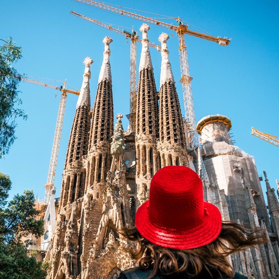 A woman in a red hat gazing up at Gaudi’s Sagrada Familia cathedral in Barcelona