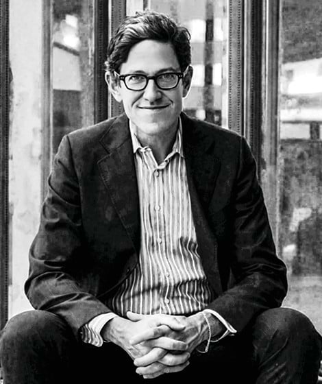 Randy Weiner sitting and smiling wearing a dress shirt and blazer