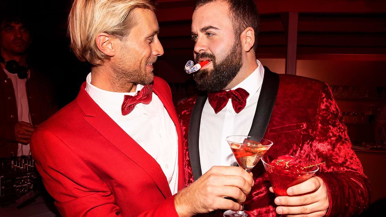 Tow man wearing red smokings toasting with martini glasses