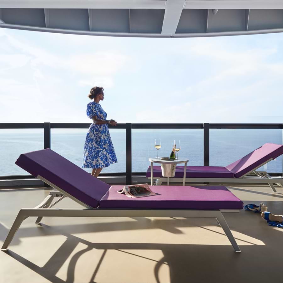 A woman standing at the ship’s railing overlooking the ocean on a spacious deck